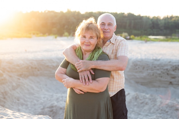 夏の公園で一緒に年配の高齢者の白人カップル 妻と夫が抱き合って幸せに笑います 美しい恋愛関係と引退した老人の世話 プレミアム写真