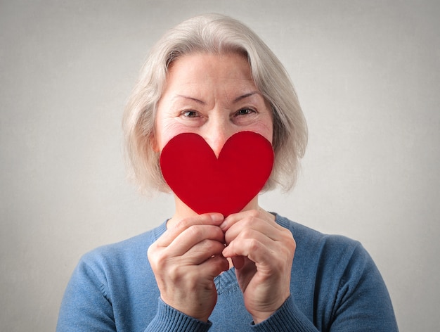 Senior lady  holding  a paper heart  Premium Photo