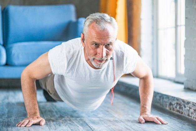 Senior man doing pushup at home Free Photo