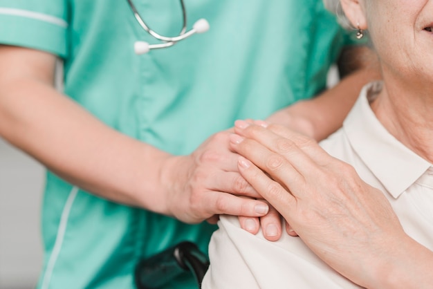 Senior woman patient touching female nurse hand on shoulder Free Photo