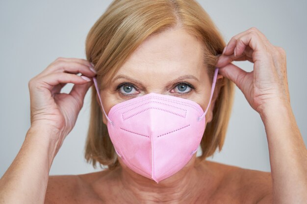 Premium Photo Senior Woman In Pink Mask Posing Over Gray Background 