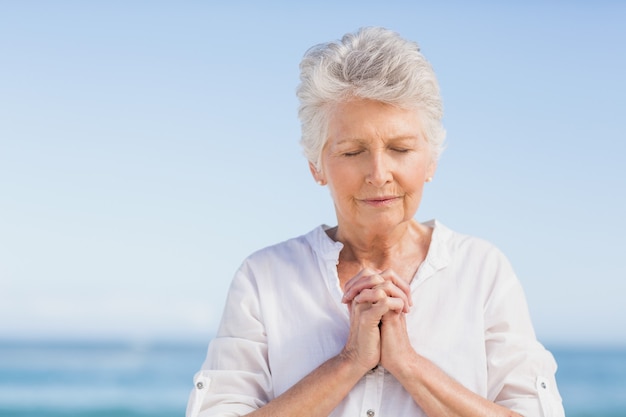 Premium Photo | Senior woman praying on the beach