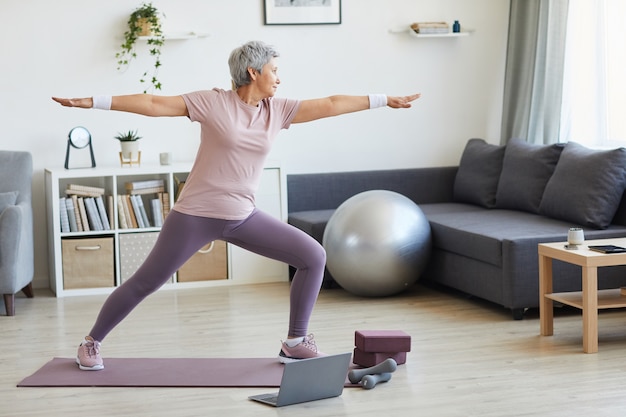 Premium Photo | Senior woman standing on exercise mat exercising during ...