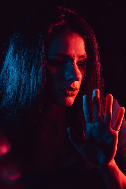Sensual portrait of sad girl through glass with raindrops with red blue  lighting | Premium Photo