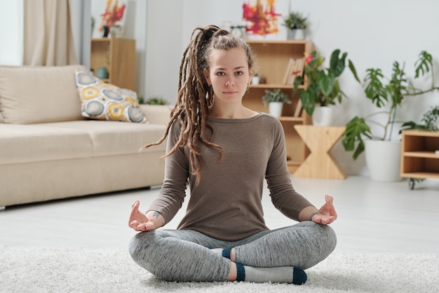 Premium Photo Serene Girl In Activewear Crossing Legs While Sitting On The Floor And Practicing Relaxing Yoga Exercise freepik