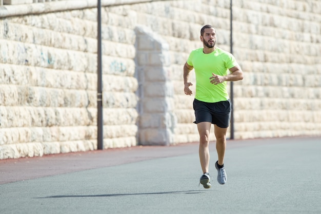 Free Photo | Serious muscular sporty man running on road