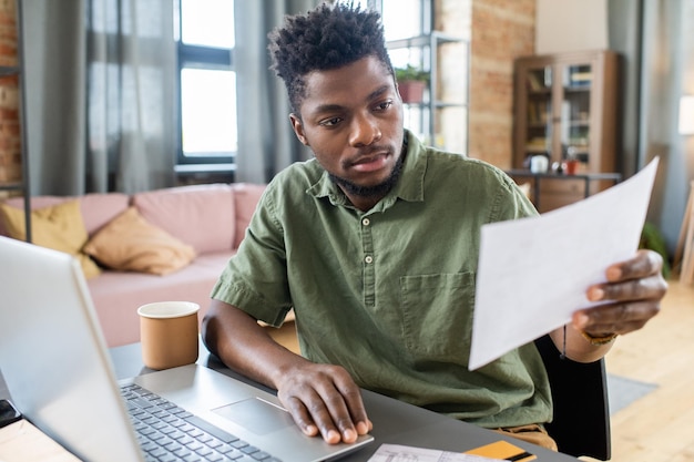 Premium Photo | Serious young african american man sitting at table ...