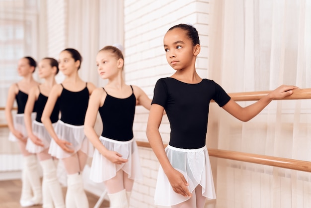 Premium Photo | Serious young ballerinas stand along ballet barre.