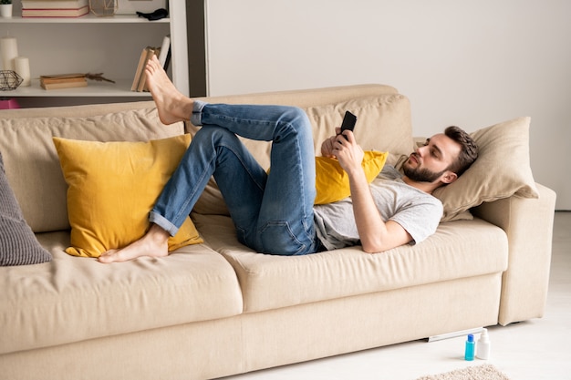 Arthur Republikeinse partij informatie Premium Photo | Serious young bearded man in jeans lying on sofa and  communicating online via smartphone messengers in home isolation