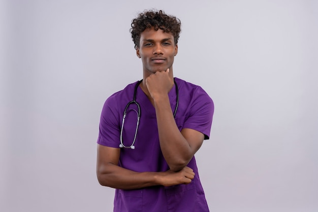 Free Photo A Serious Young Handsome Dark Skinned Doctor With Curly Hair Wearing Violet Uniform 8625