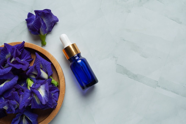 Serum bottle of butterfly pea flower oil put on white marble background Free Photo