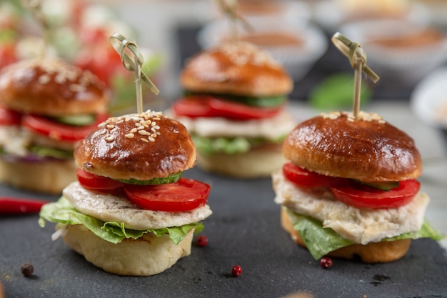 Premium Photo | Set of chicken burgers on black board on wooden table