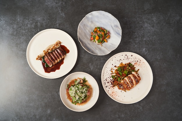 Set of various plates of food on a gray table background with copy