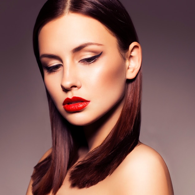 Sexy brunette woman with cat eyes and red lips make up on a neutral dark background. flawless skin Premium Photo