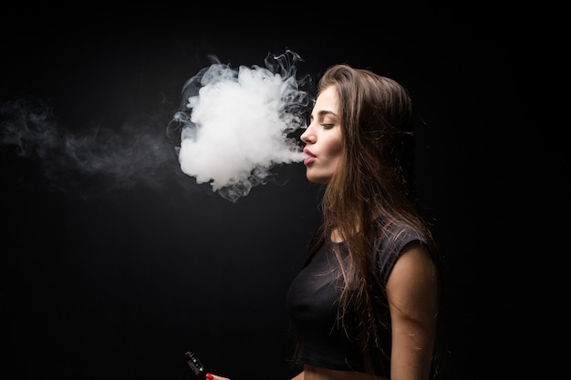 無料の写真 暗い壁に電子タバコを吸って黒いドレスのセクシーな女の子