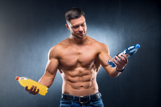 Premium Photo Sexy Sportsman Holding A Bottle Of Water And Soda