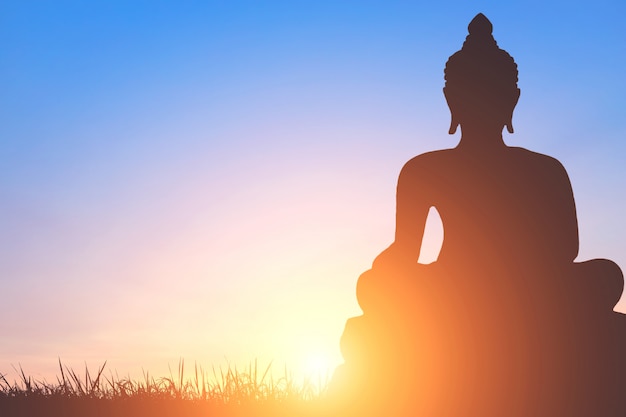 Premium Photo | Shadow of buddha statue on golden sunset sky background