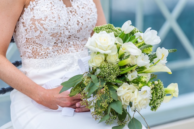 花の花束を持っているウェディングドレスの花嫁の浅いフォーカスショット 無料の写真
