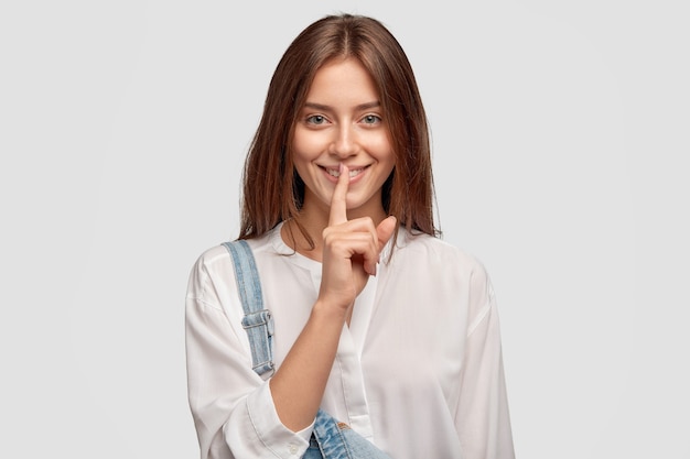 Free Photo | Shh, its privacy! good looking dark haired woman with charming smile, keeps index finger over mouth