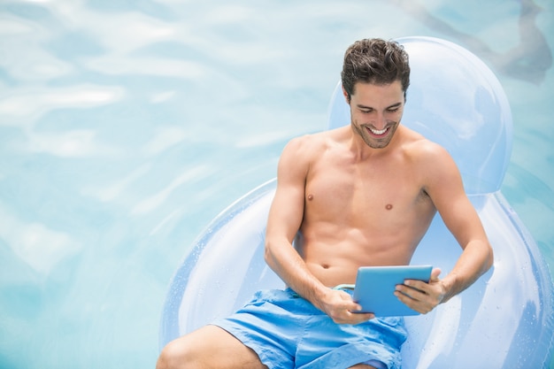 Premium Photo | Shirtless man using digital tablet on swim ring