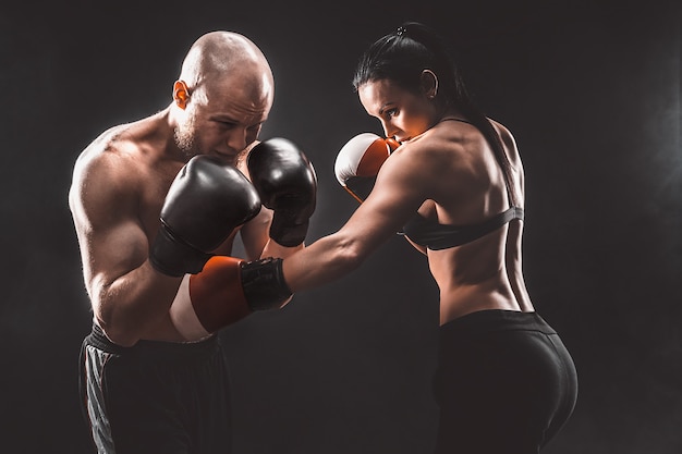 Premium Photo | Shirtless woman exercising with trainer at boxing and ...