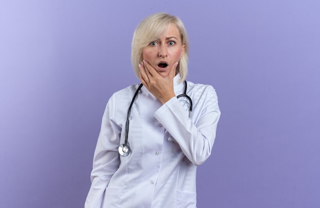 Free Photo Shocked Adult Slavic Female Doctor In Medical Robe With Stethoscope Holding Chin