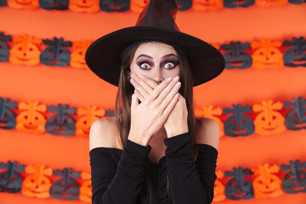 Premium Photo | Shocked witch girl in black halloween costume covering ...