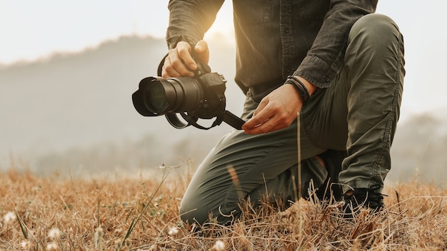 風景の景色を撮影 カメラを保持しながら若いアジアの男性写真家のクローズアップ プレミアム写真