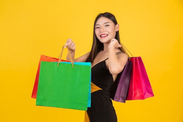 Download Free Photo Shopping Beautiful Woman Holding A Colorful Paper Bag On A Yellow PSD Mockup Templates
