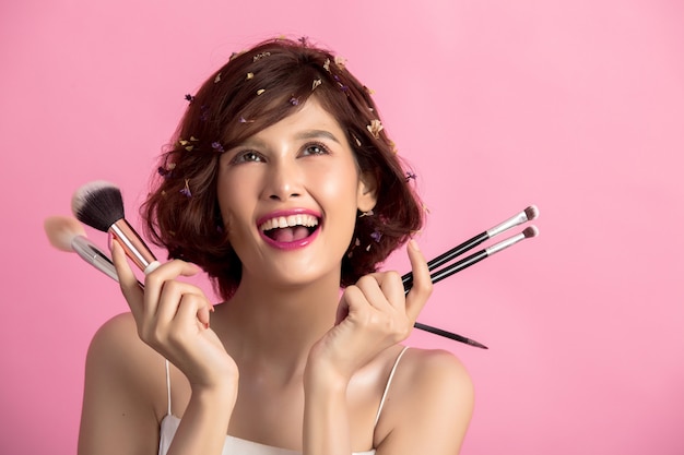 Short hair asian young beautiful woman applying cosmetic powder brush Free Photo