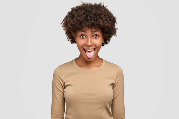 面白い黒人女性のショットは舌を示し 遊び心のある表現 アフロの髪型を持っています 無料の写真