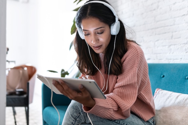 shot-pretty-young-woman-listening-music-with-digital-tablet-while-sitting-sofa-home_519356-1671.jpg