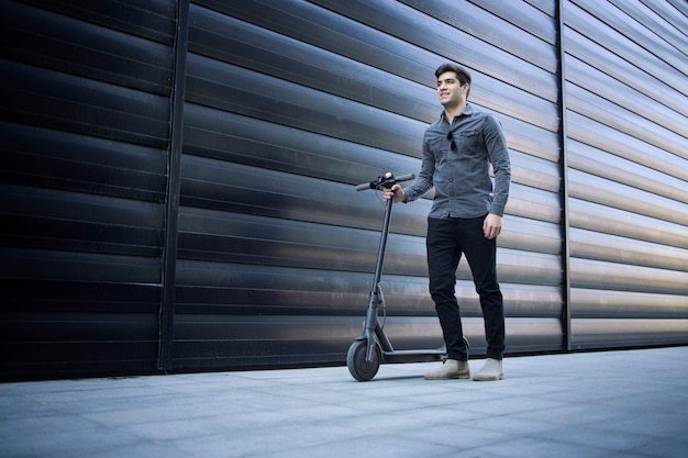 Shot of young handsome man standing by his electric scooter on the street Free Photo