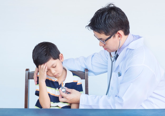 Sick asian boy being examined by male doctor over white background Free Photo
