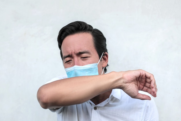 Premium Photo | Sick man wearing a face mask and coughing in his elbow