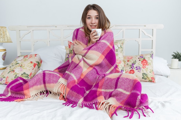 一杯のお茶を保持している毛布で覆われている病気の女性 無料写真