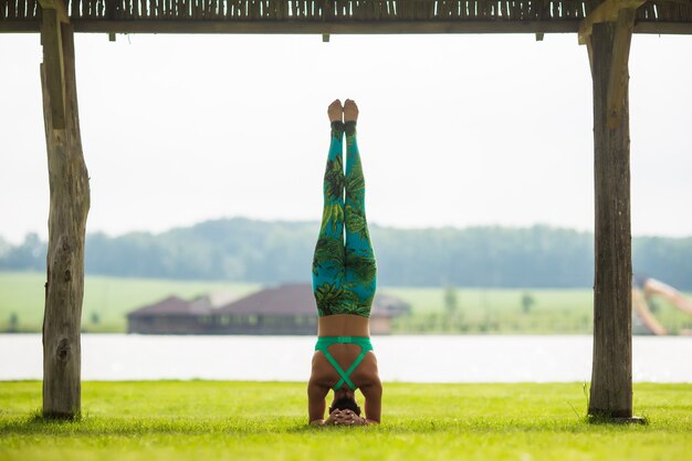 Side view of barefoot young concentrated woman doing handstand in park in summer day Free Photo