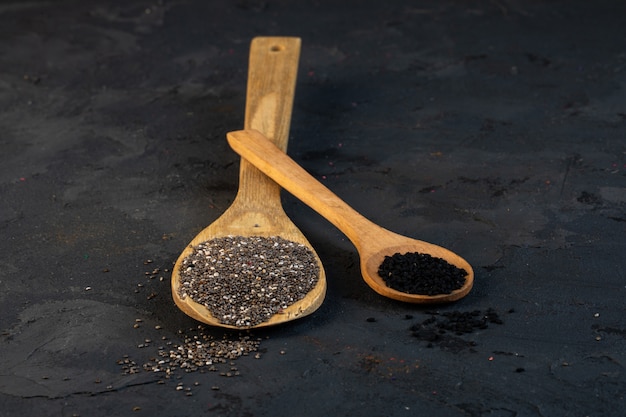 Side view of black cumin seeds in wooden spoons on black Free Photo