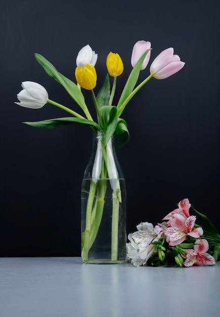 Side view of a bouquet of colorful tulip flowers in a glass bottle and