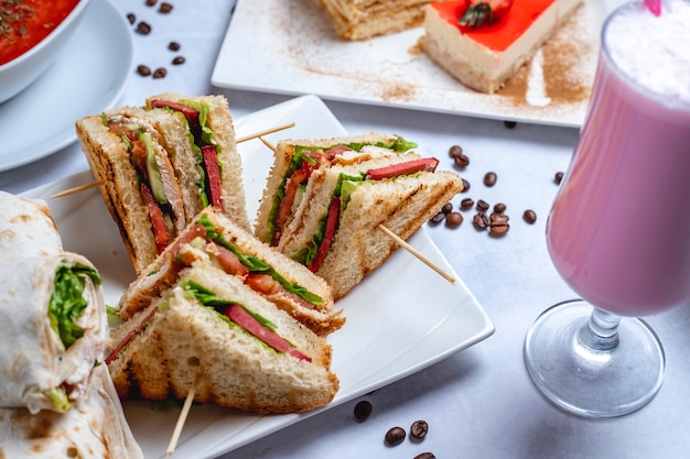 Free Photo Side View Club Sandwich Grilled Chicken With Cucumber Tomato Sauce Lettuce Milkshake And Coffee Beans On The Table