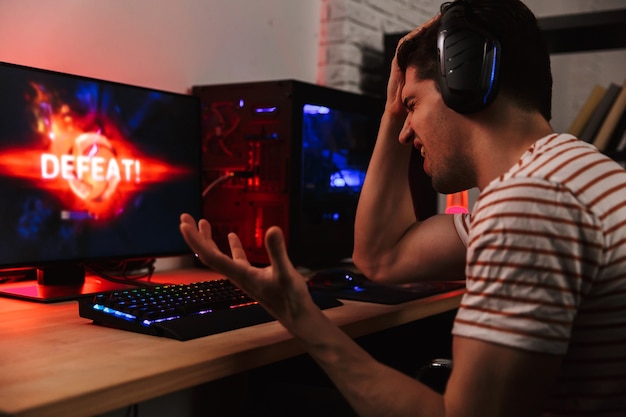 Premium Photo | Side view of confused gamer playing video games on computer