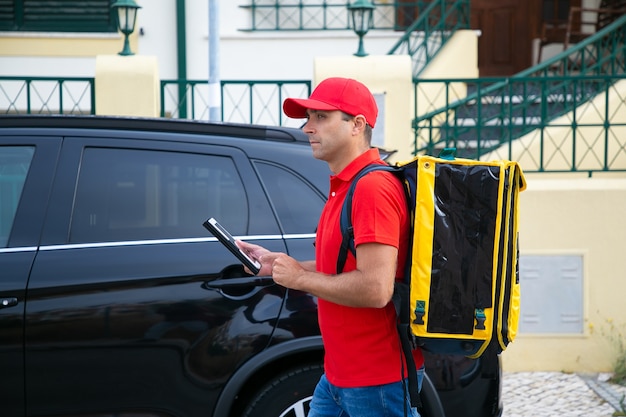 Free Photo | Side view of deliveryman watching address on tablet ...