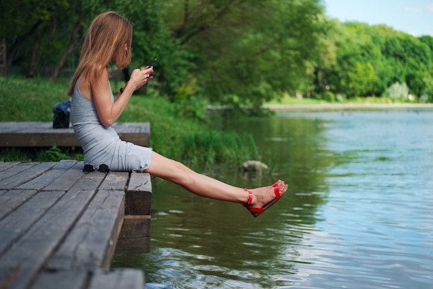 Premium Photo | Side view of a girl sitting on wooden pier on river ...