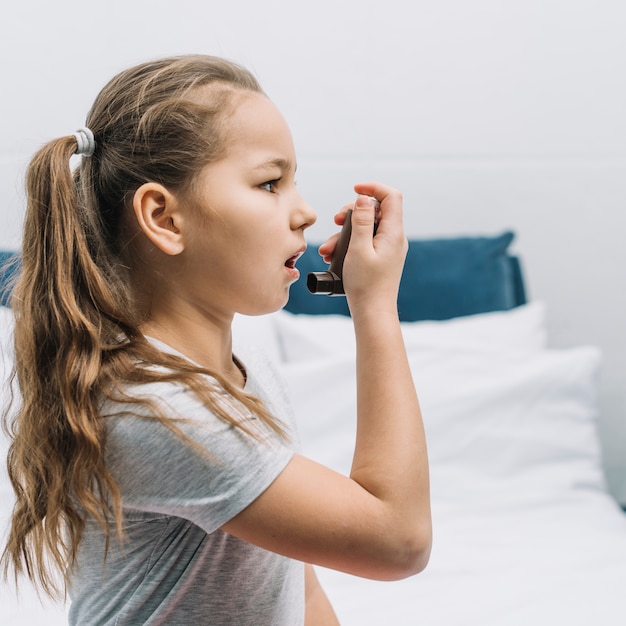 Side view of a girl using asthma inhaler Free Photo