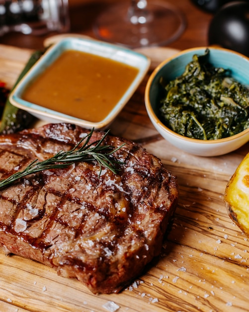 Free Photo | Side view of grilled beef steak with sauce on a wooden board