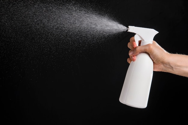 Side view of hand with surgical glove spraying disinfectant | Free Photo