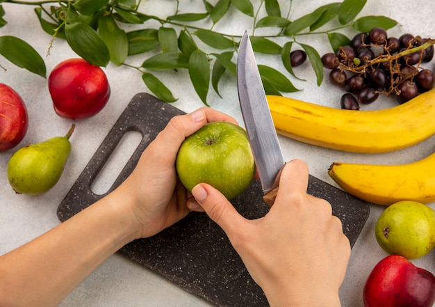 Free Photo | Side view of hands slicing apple with knife on cutting ...