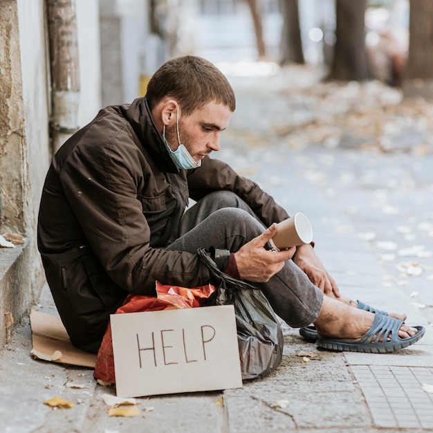 Free Photo | Side View Of Homeless Man Outdoors With Help Sign And Cup