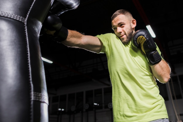 Free Photo | Side view of male boxer practicing with punching bag