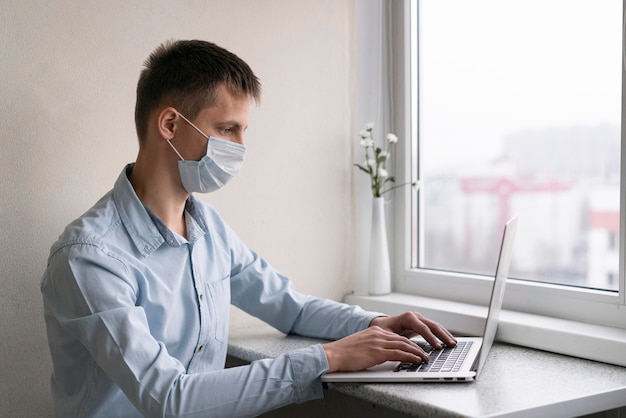 Side view of man with medical mask working on smartphone Free Photo
